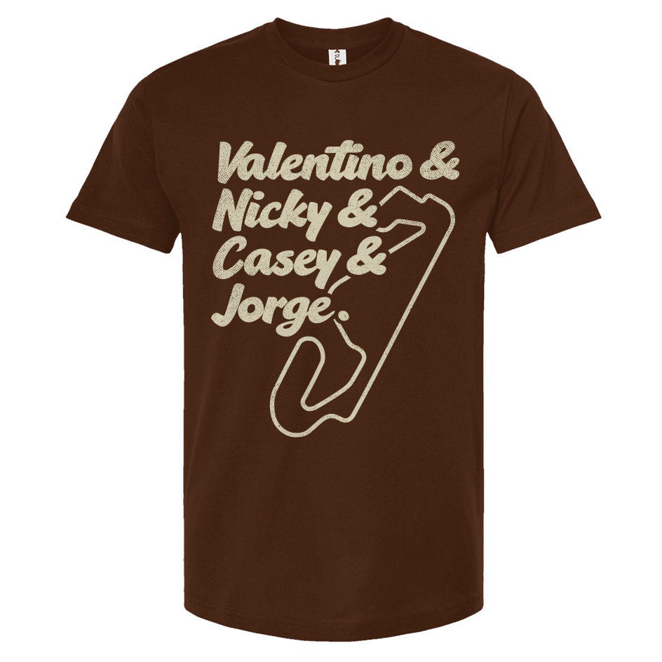 A crewneck t-shirt with text and a graphic design in a cream color. The text lists 'Valentino & Nicky & Casey & Jorge' with a stylized representation of a motorcycle track beneath it.
