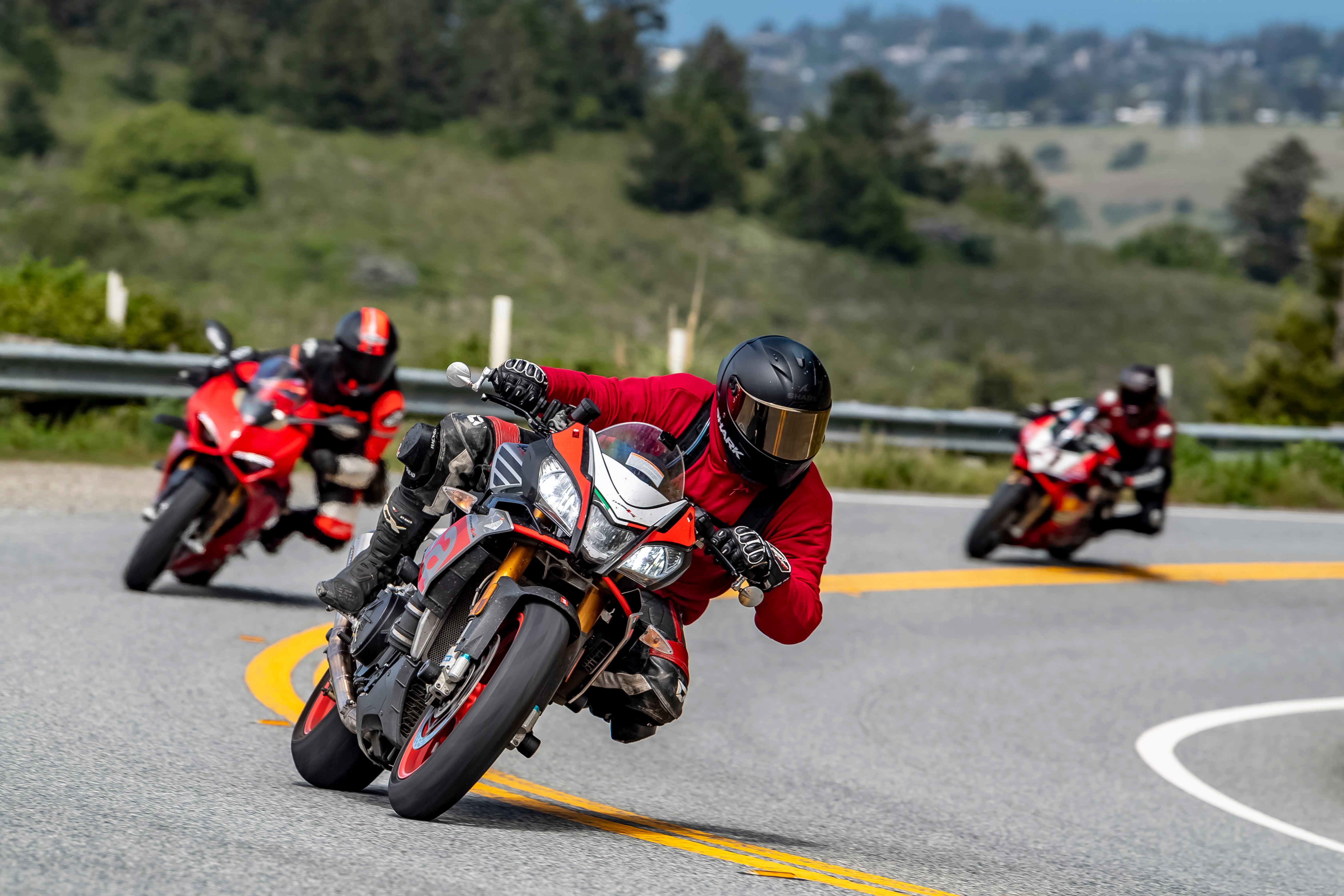 Motorcycles riding around a turn aggressively with scenic background