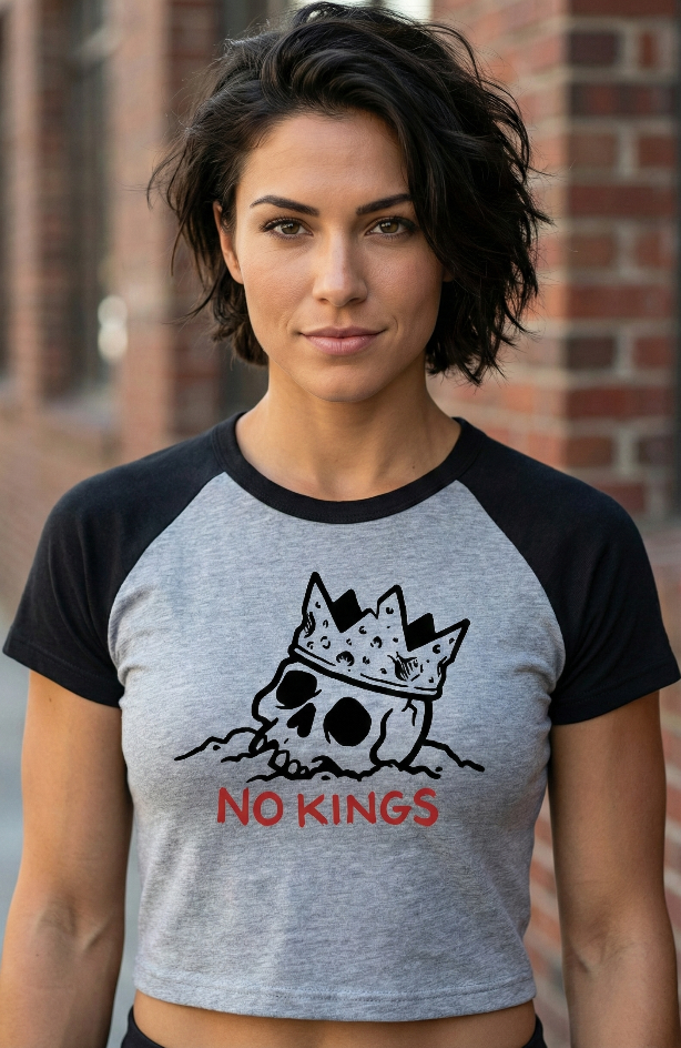 Woman wearing a gray and black t-shirt with a skull and crown design and 'No Kings' text.