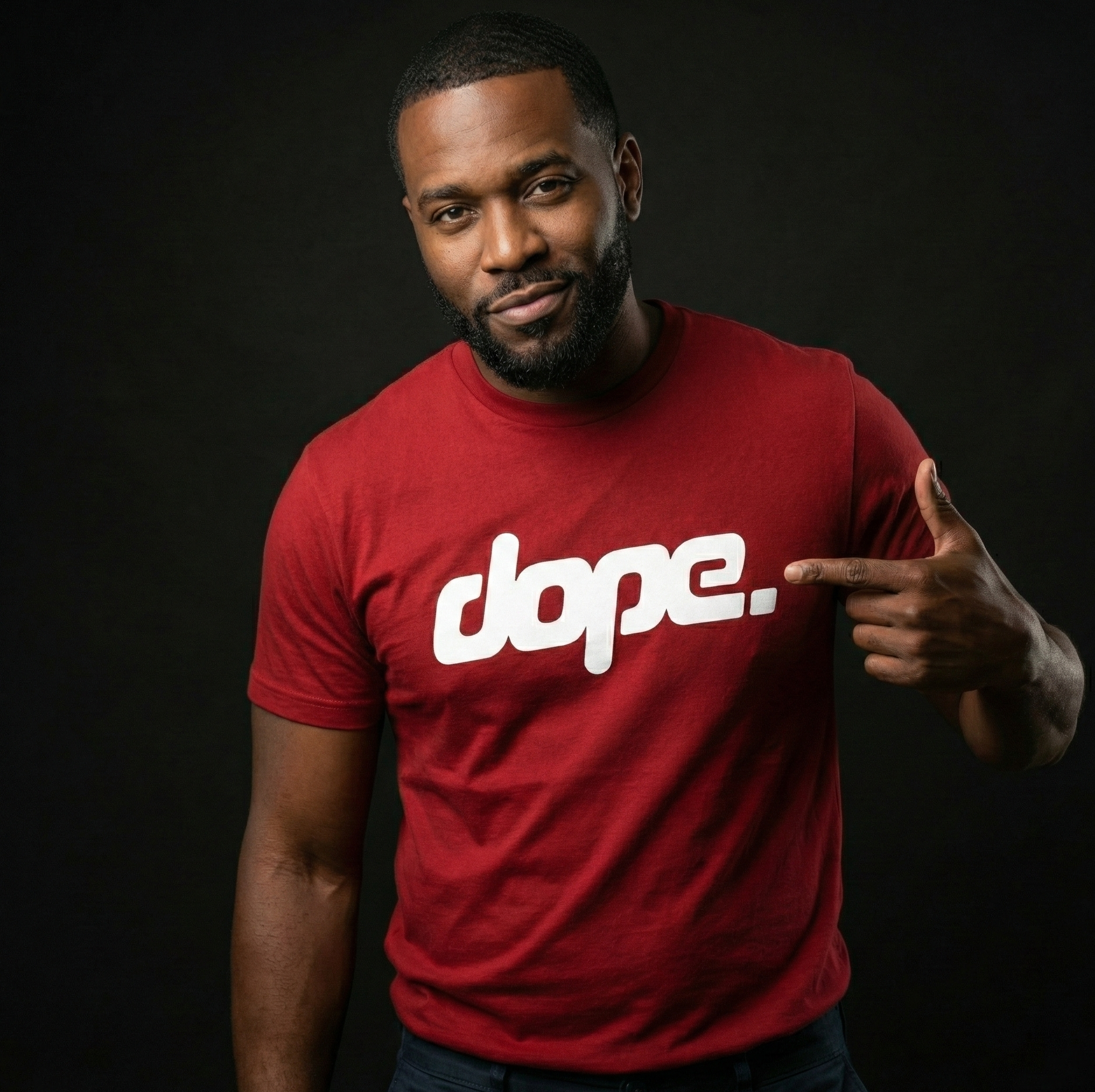 Man wearing a cardinal red 'dope.' t-shirt pointing to the text on a black background