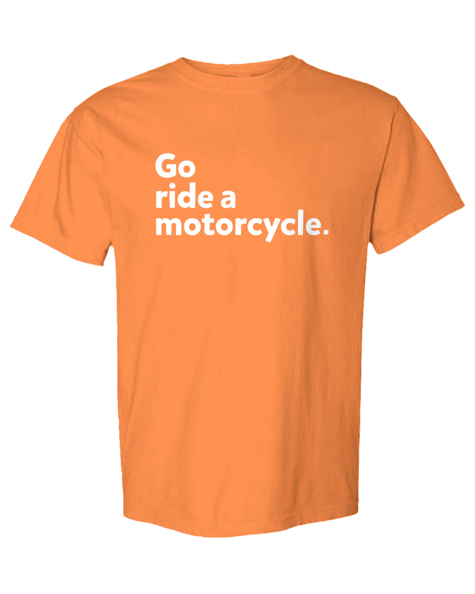 An orange short-sleeve crewneck t-shirt with the phrase 'Go ride a motorcycle.' printed in white sans-serif text on the chest