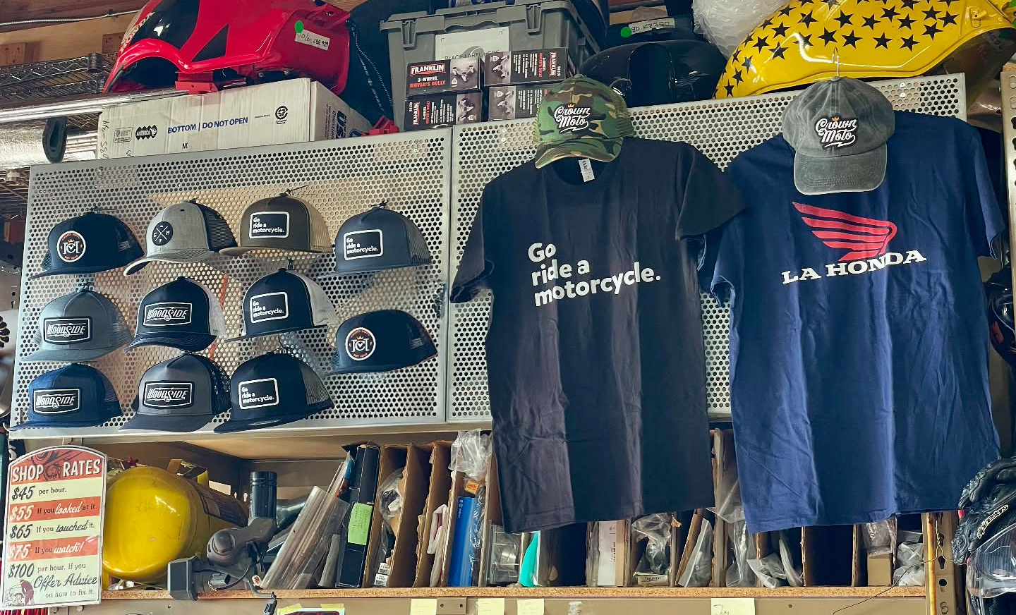 Image of Crown Moto motorcycle hats and t-shirts displayed on a wall in a garage