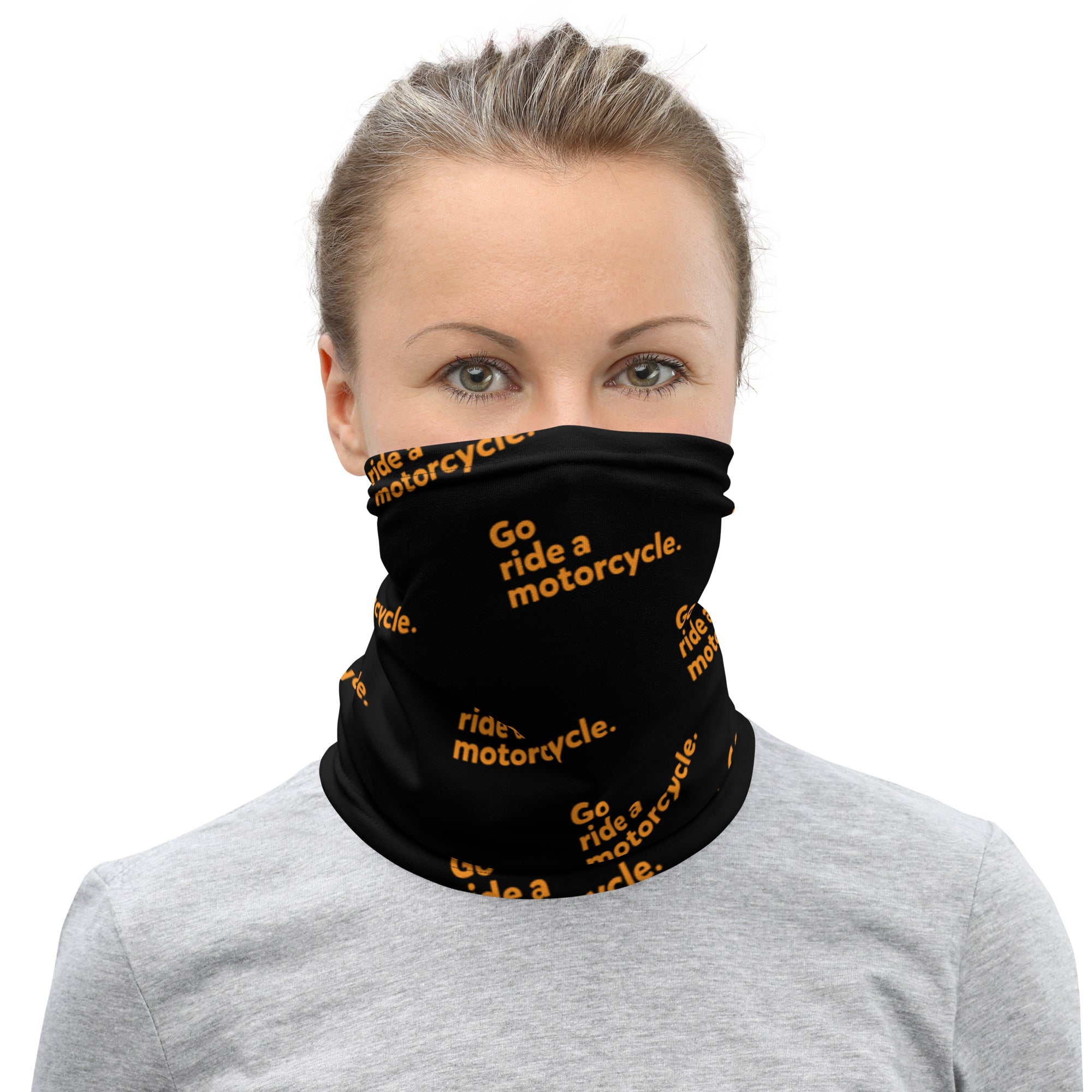 Woman wearing black and orange "Go ride a motorcycle" neck gaiter with text repeated at an angle on premium neck gaiter sleeve