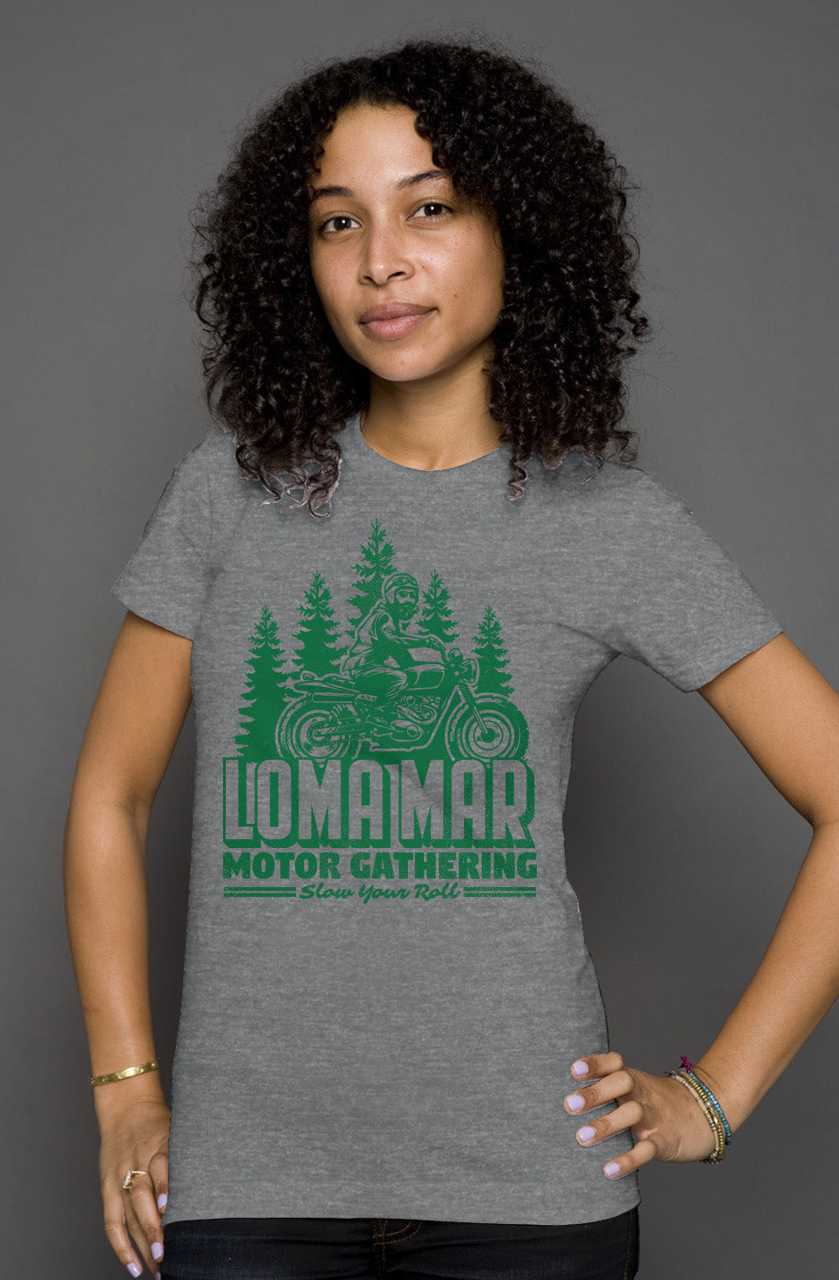 Woman wearing grey short sleeve t-shirt with original Loma mar motor gathering scrambler motorcycle design on chest in green