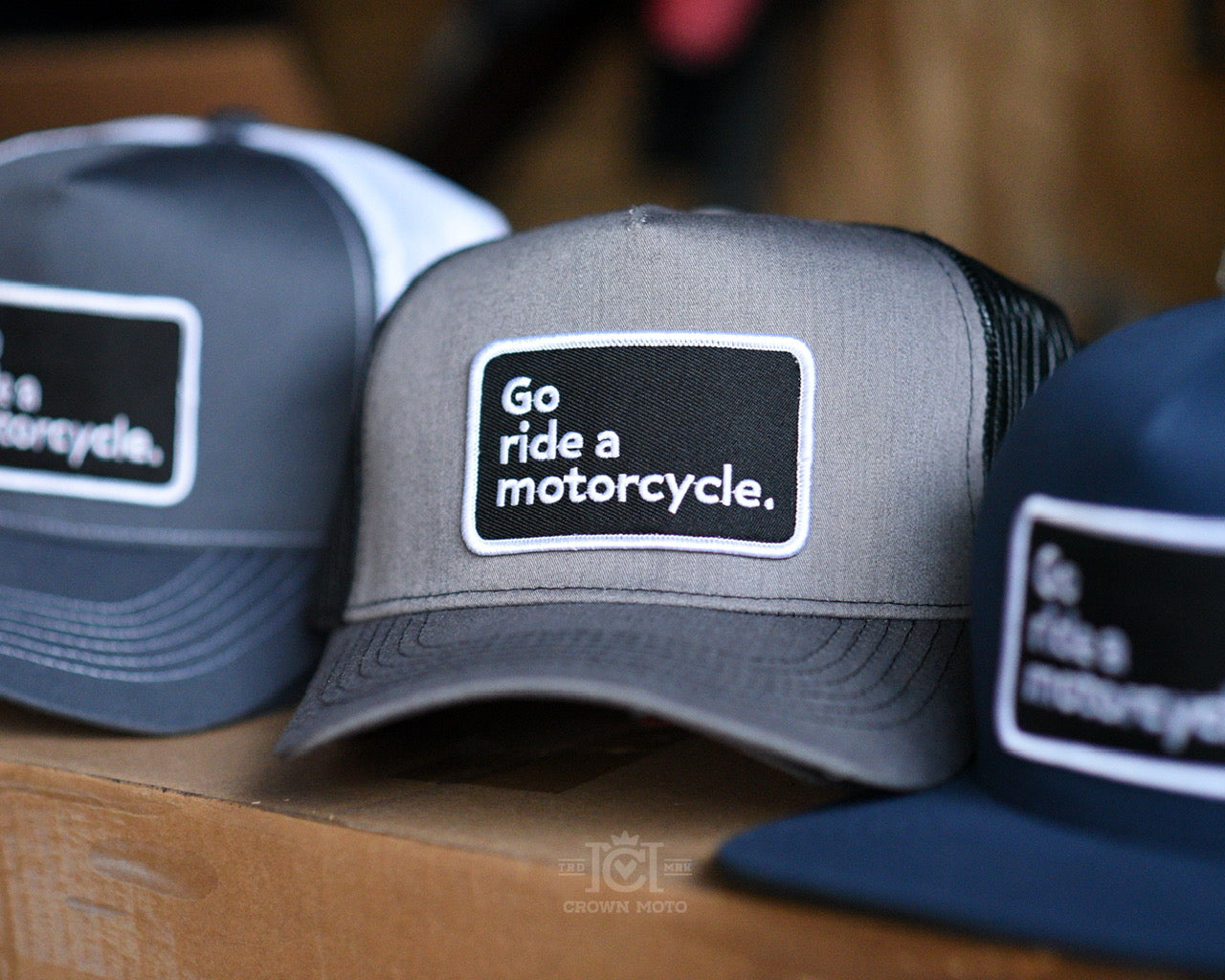 "Go ride a motorcycle" patch trucker hats on shelf made and sold by "Crwn Moto"