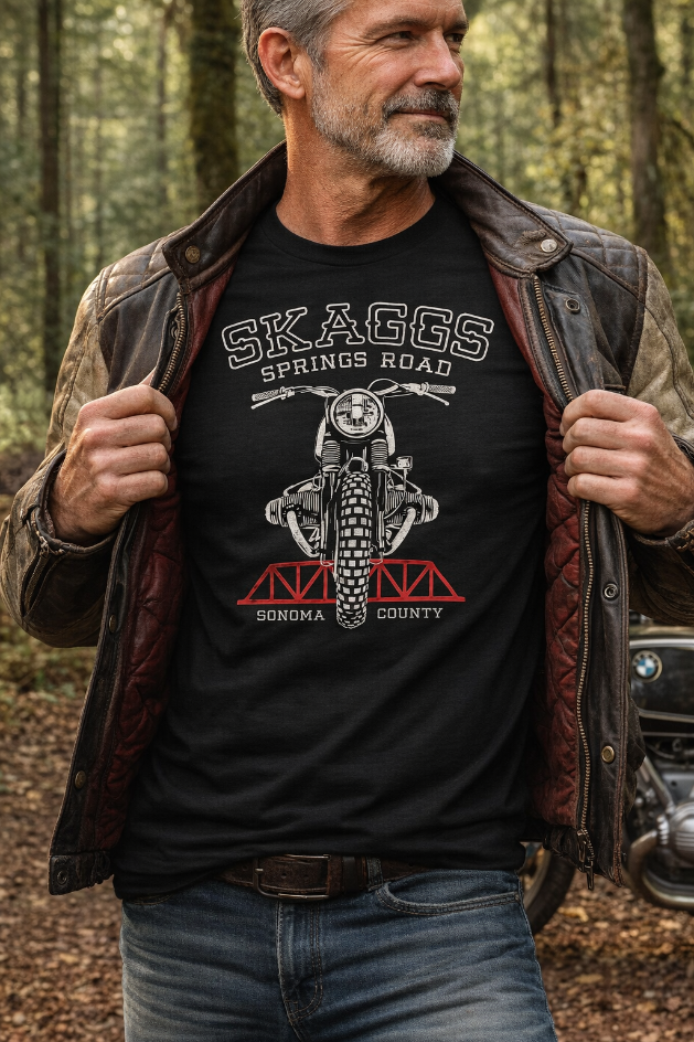 Man wearing a black t-shirt with a Skaggs Springs Bridge Motorcycle design in a forest setting