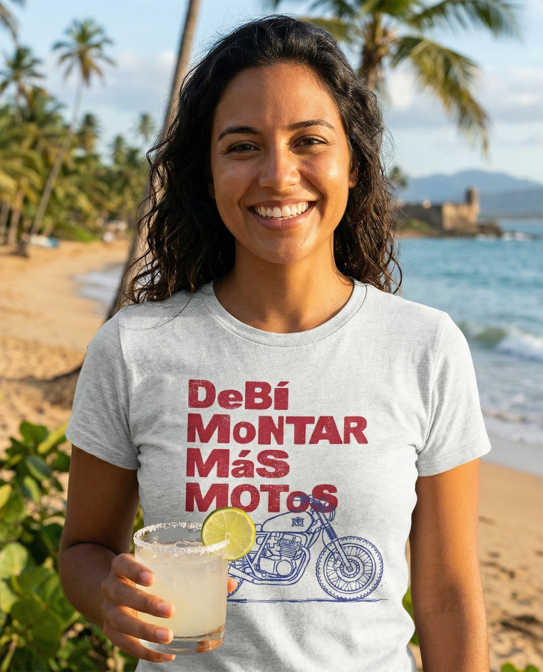 Beautiful latina woman wearing a 'Debi montar mas motos' t-shirt at the beach with a drink in her hand