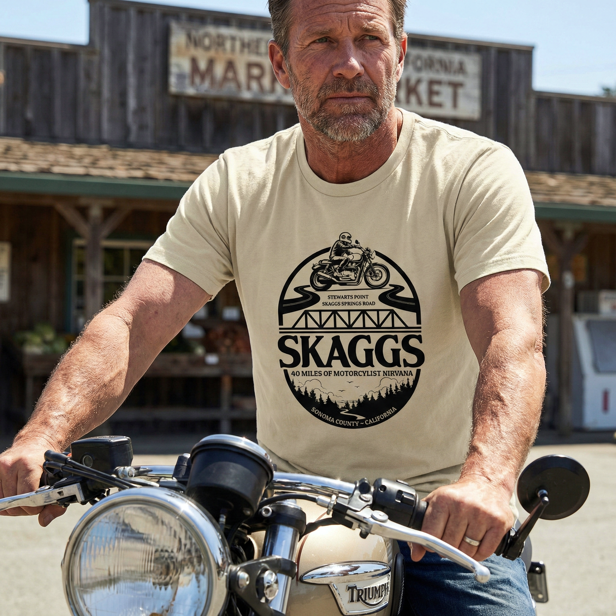 Man wearing a beige t-shirt with 'SKAGGS' design on a motorcycle.