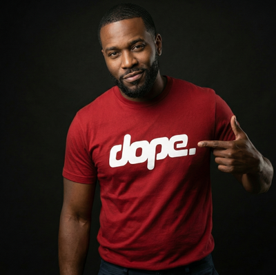 Man wearing a cardinal red 'dope.' t-shirt pointing to the text on a black background