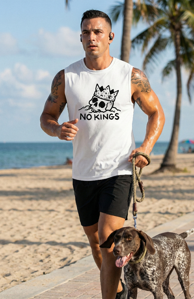 Man wearing a NO KINGS Sleeveless Workout Tee running at the beach with his dog
