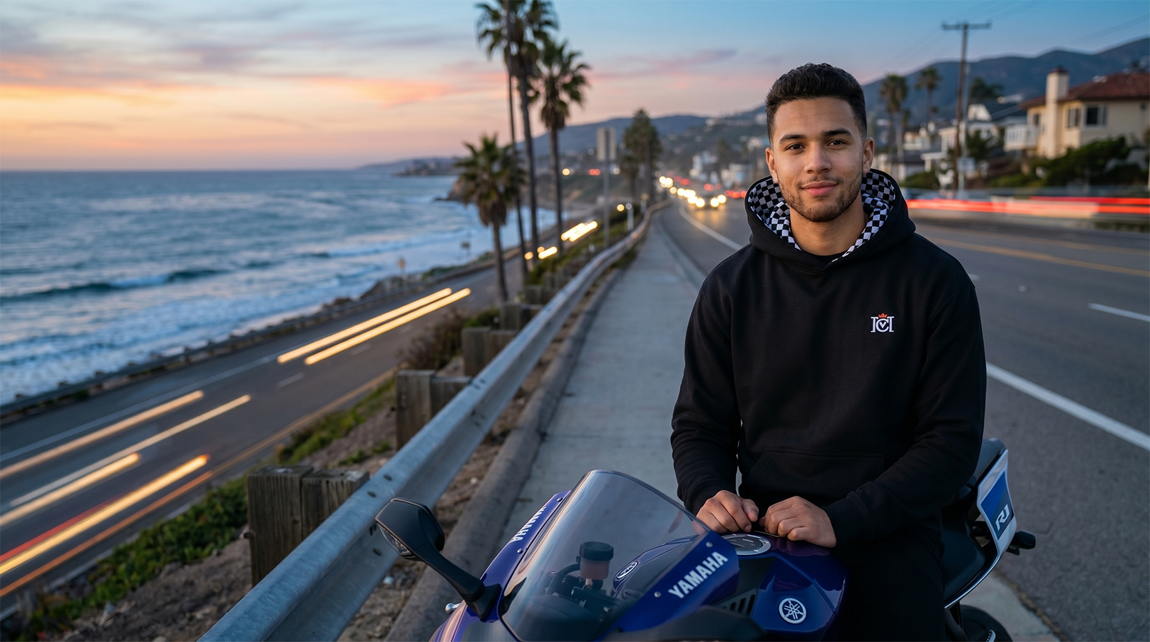 Man sitting on motorcycle at the beach wearing a crown moto armored hoodie with checkered flag lined hood