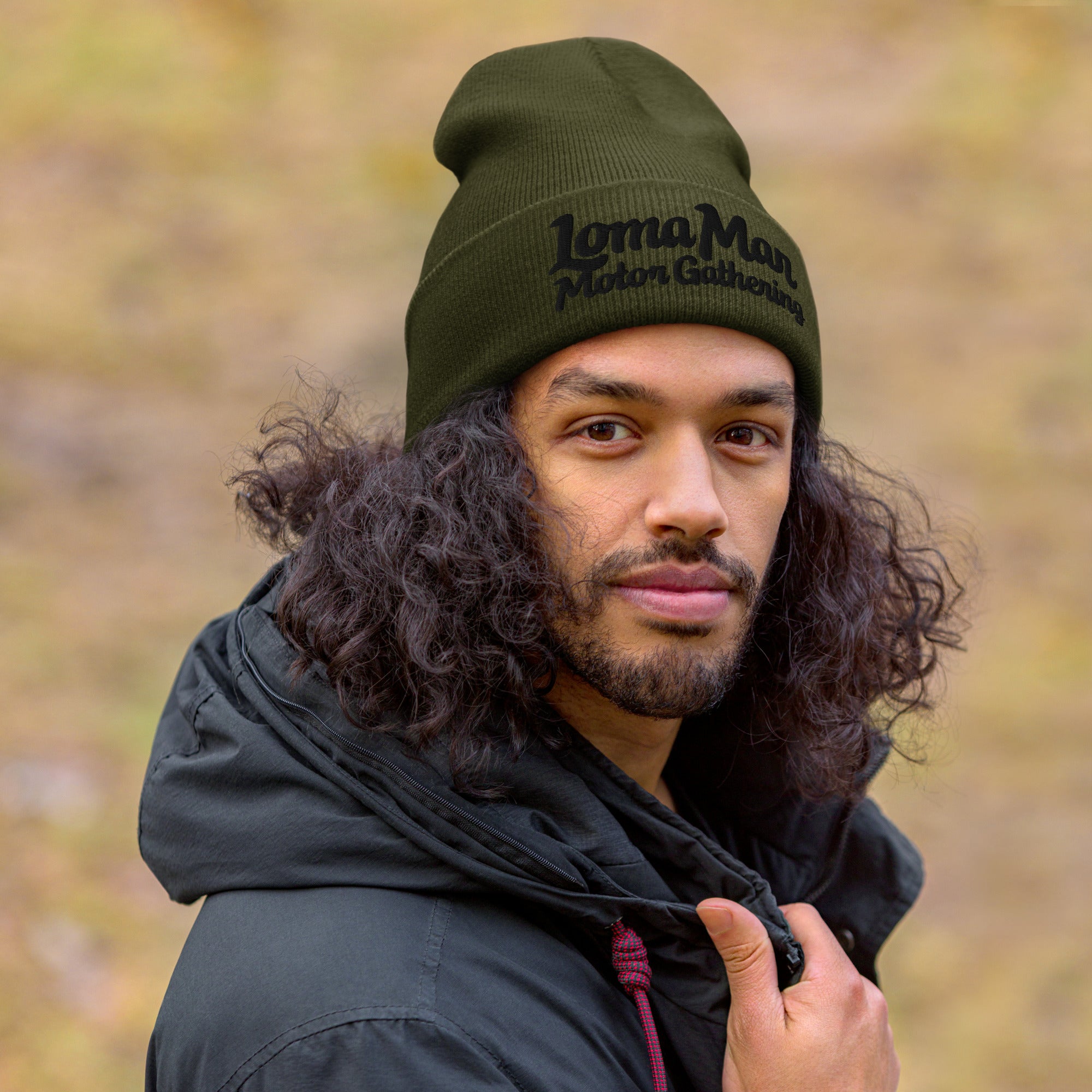 Man wearing green knit beanie with "Loma Mar Motor Gathering" embroidered on cuff of beanie