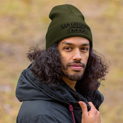 man wearing green beanie with San Gregorio General Store design embroidered on cuff