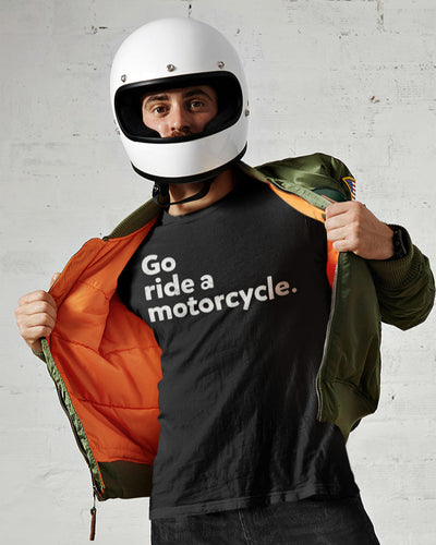 Man wearing motorcycle helmet and opening jacket to show black t-shirt with "Go ride a motorcycle" design printed on chest