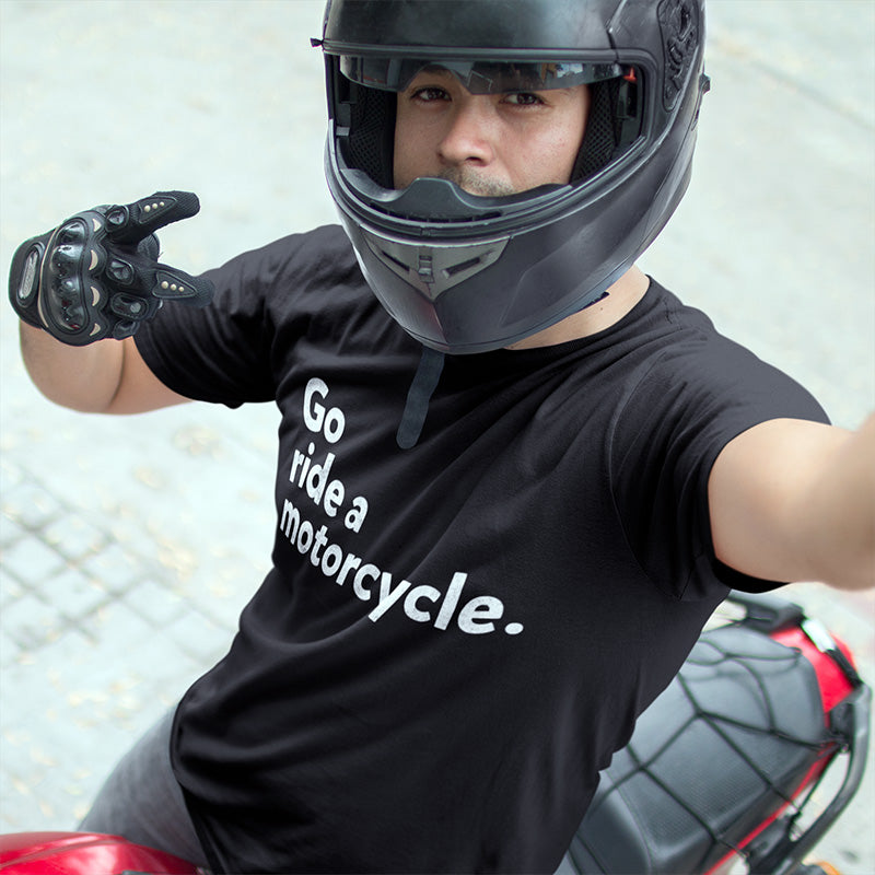 Man sitting on a motorcycle wearing a helmet and a black t-shirt with "Go ride a motorcycle" printed on chest