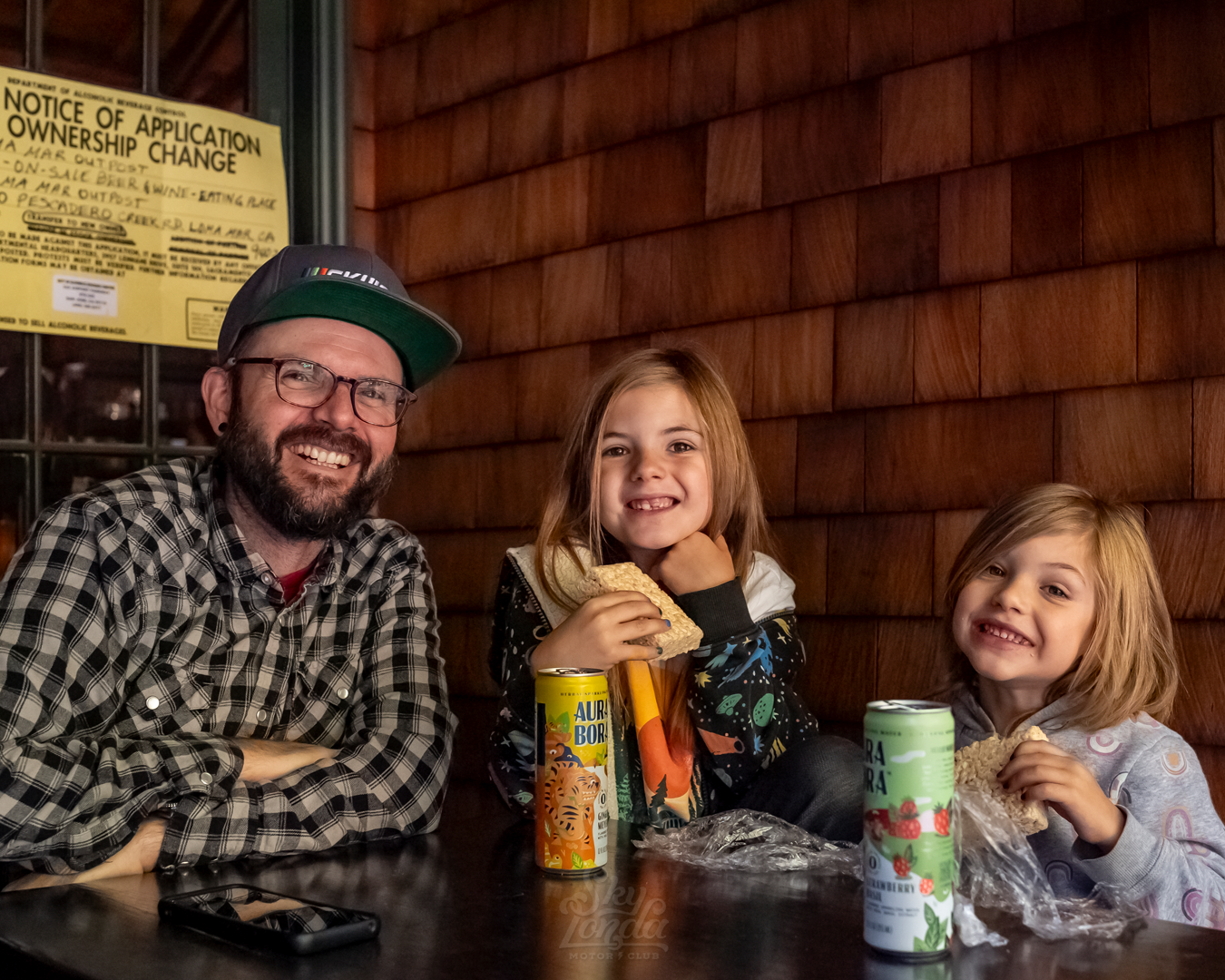 Man sitting with his two kids at the Loma Mar Motor Gathering in Loma Mar, CA, cars and coffee event founded and hosted by Crown Moto