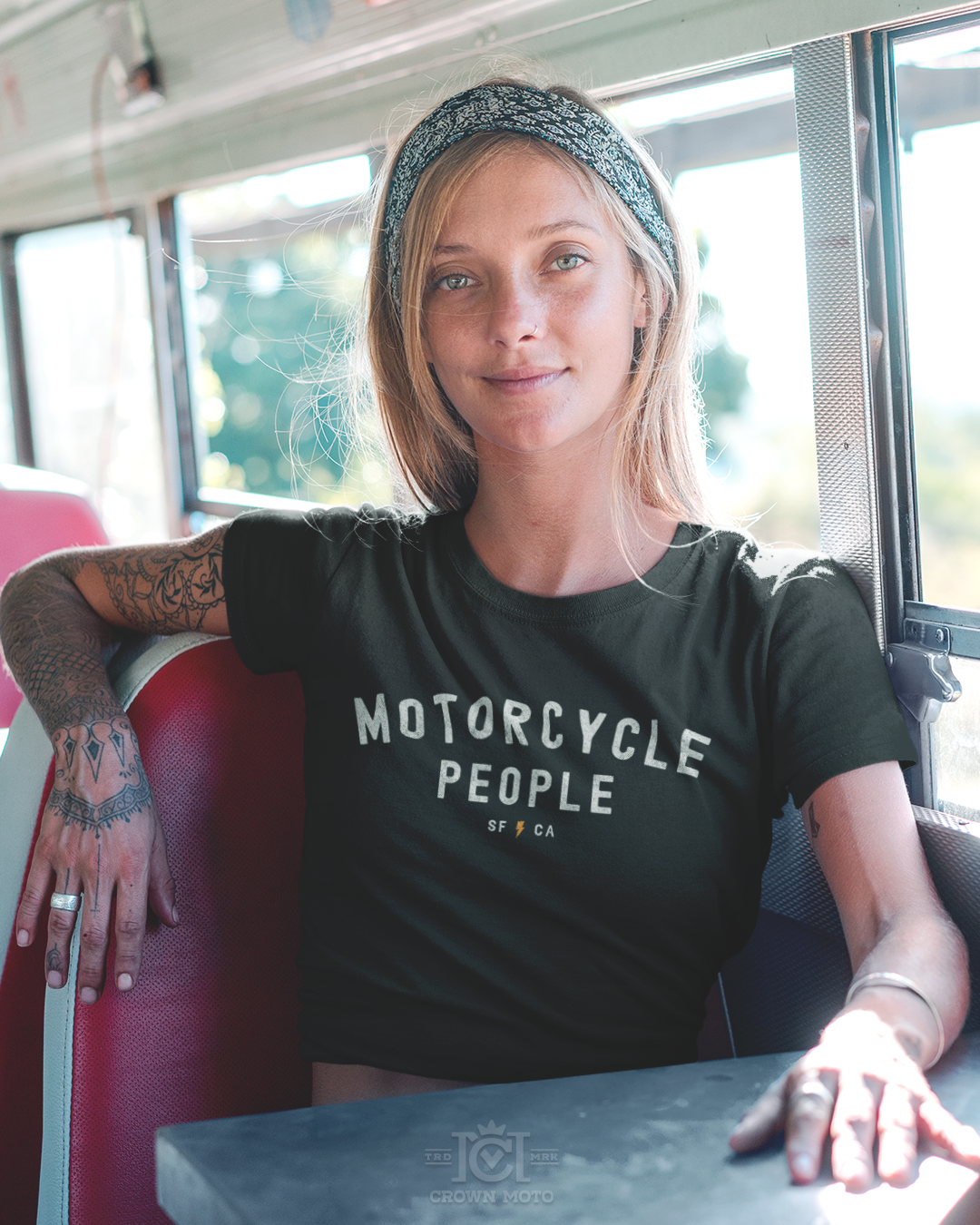 woman sitting in a bus wearing a "motorcycle people" SF CA short sleeve cropped t-shirt