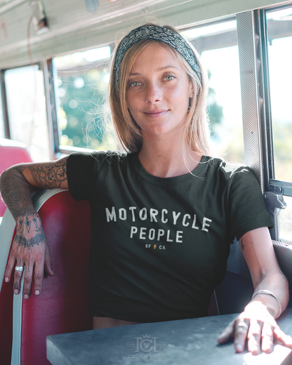 woman sitting in a bus wearing a "motorcycle people" SF CA short sleeve cropped t-shirt