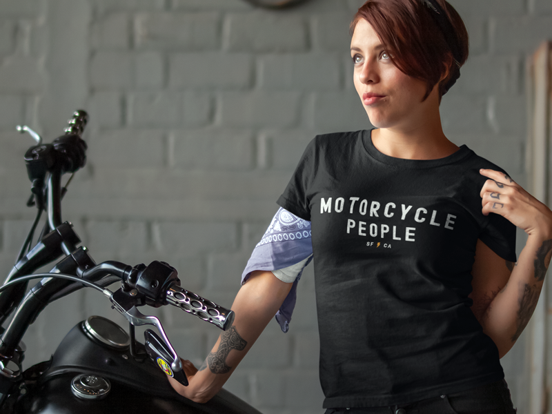 Woman standing next to motorcycle wearing "motorcycle people" SF CA short sleeve t-shirt