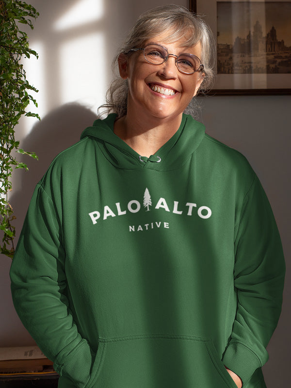 Older woman smiling wearing Palo Alto Native green hooded sweatshirt