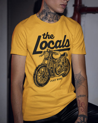 Young man with tattoos wearing a mustard gold The Locals Motorcycle Club Cafe Racer t-shirt