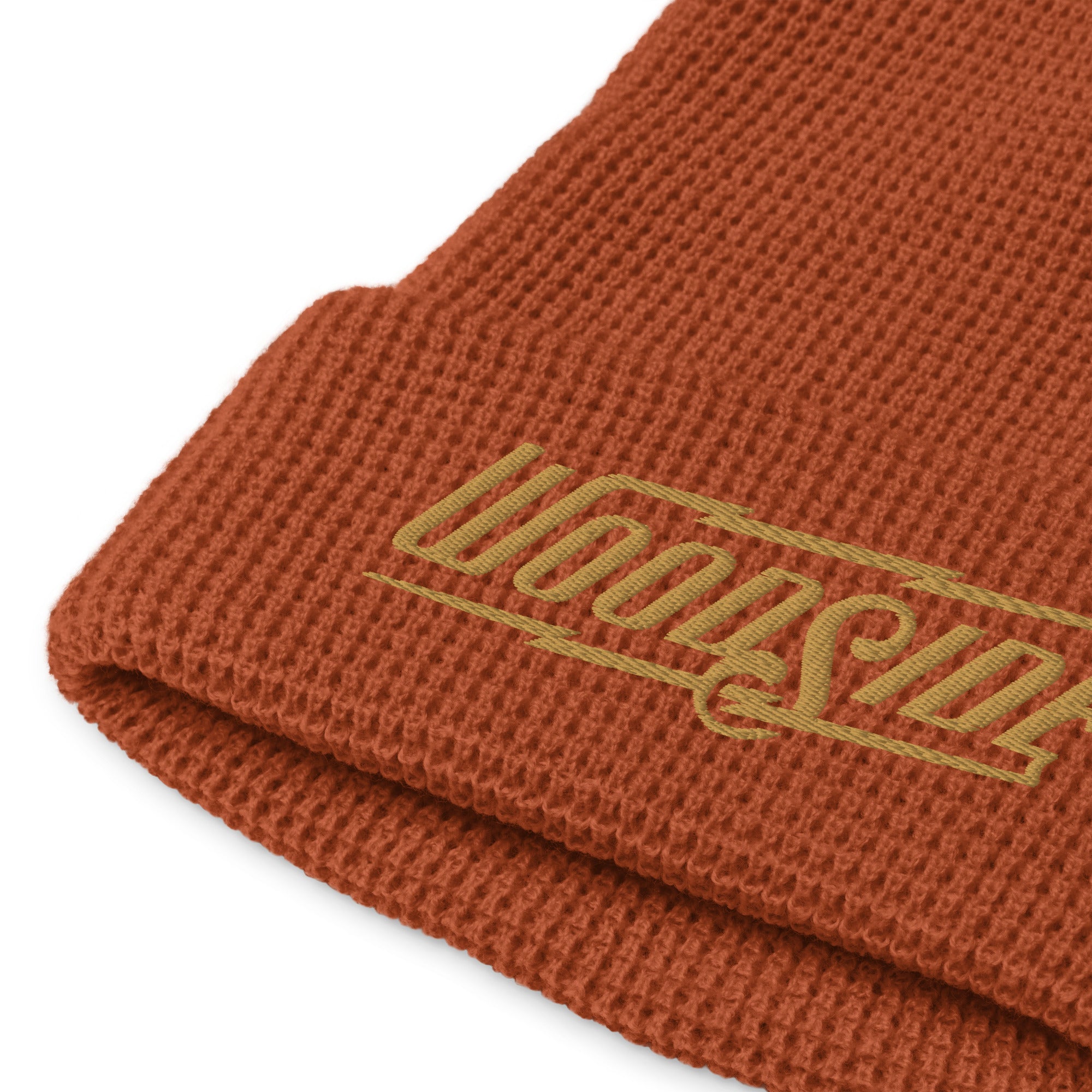 Product mockup of Woodside brand waffle knit beanie in rust color with Woodside Brand logo embroidered in gold on front cuff