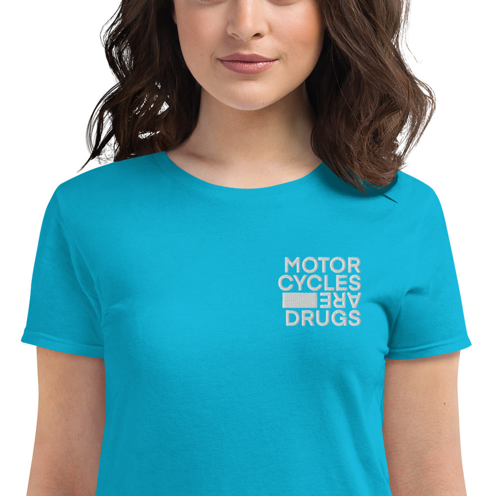 woman wearing short sleeve t-shirt with "Motorcycles are drugs" logo embroidered in white on left chest