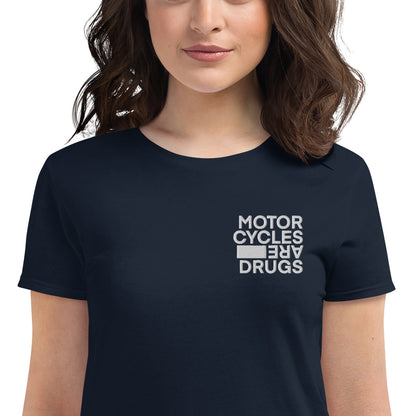 woman wearing short sleeve t-shirt with "Motorcycles are drugs" logo embroidered in white on left chest